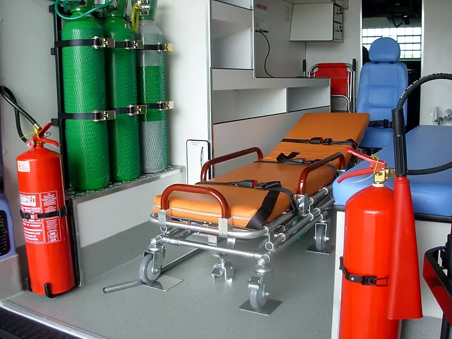 Interior de ambulância com maca, cilindros de oxigênio, extintores e armários